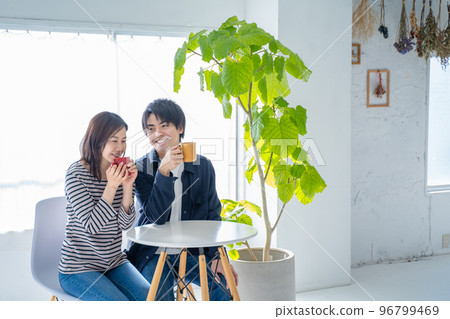 Young smiling conversational couple drinking coffee in bright living room 96799469