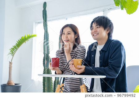 Young smiling conversational couple drinking coffee in bright living room 96799492