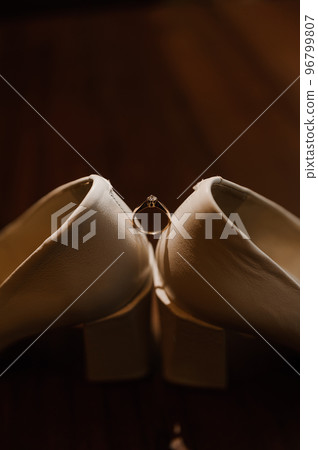 Ring with a stone on white women's leather shoes. Bride's accessories, bride's morning Ring with a stone on white women's leather shoes. Bride's accessories, bride's morning 96799807