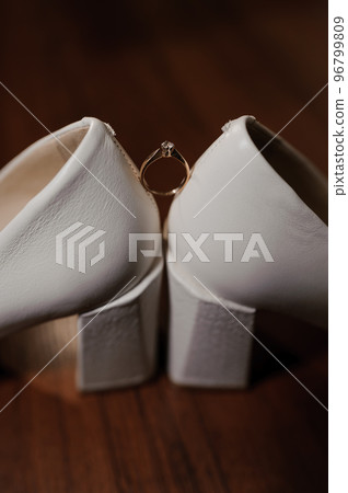 Ring with a stone on white women's leather shoes. Bride's accessories, bride's morning Ring with a stone on white women's leather shoes. Bride's accessories, bride's morning 96799809