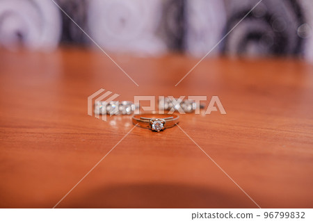 Earrings, gold ring with a gem on a brown background Earrings, gold ring with a gem on a brown background 96799832