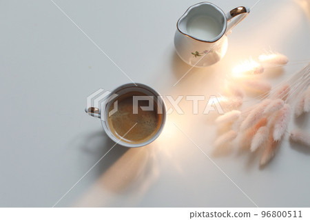 cup with coffee and milk jug on a white wooden background, closeup. Energy breakfast, morning routine concept 96800511