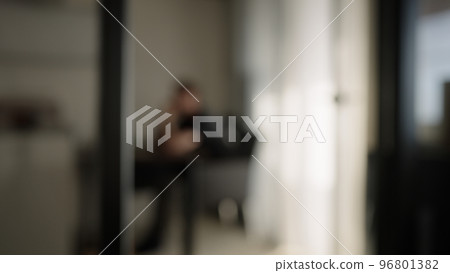 Blurred background of one man sitting in diningroom with natural window light 96801382