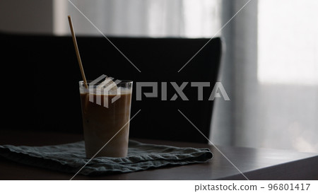 man making iced coffee with milk in thumbler glass on walnut table 96801417