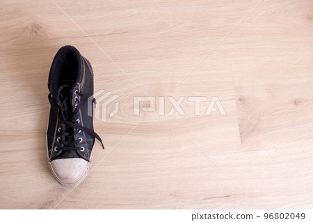 Old torn black shoe on a wooden background 96802049