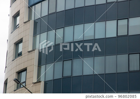 Tall glass modern building against a gray sky Tall glass modern building against a gray sky 96802085