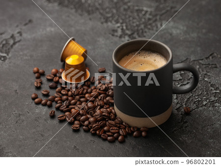 Coffee cup with fresh raw beans and coffee capsules on black Coffee cup with fresh raw beans and coffee capsules on black 96802201