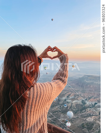 Happy woman during sunrise watching hot air balloons in Cappadocia, Turkey Happy woman during sunrise watching hot air balloons in Cappadocia, Turkey 96803324