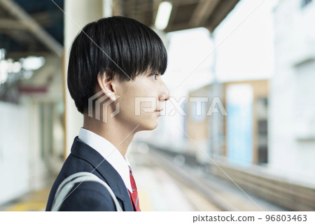 Male high school student waiting for a train at the station platform 96803463
