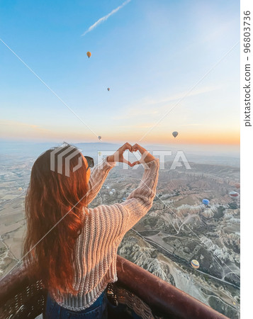 Happy woman during sunrise watching hot air balloons in Cappadocia, Turkey Happy woman during sunrise watching hot air balloons in Cappadocia, Turkey 96803736
