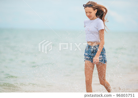 Little happy girl splashing and running in clear turquoise water Little happy girl splashing and running in clear turquoise water 96803751