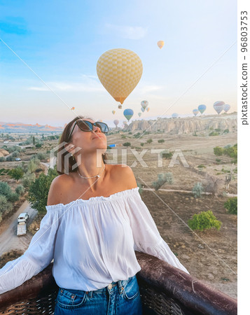 Happy woman during sunrise watching hot air balloons from a basket in the sky in Cappadocia, Turkey Happy woman during sunrise watching hot air balloons from a basket in the sky in Cappadocia, Turkey 96803753