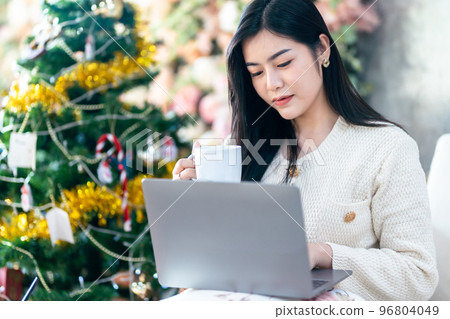 asian freelance business young woman wearing warm clothes enjoys drinking holding of positive the having cup of coffee,milk online working with laptop computer in the living room inside or cafe 96804049