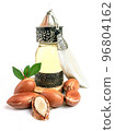 Argan oil in a oriental glass and metal bottle and argan nuts with green leaves isolated on white background. 96804162
