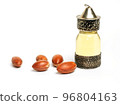 Argan oil in a oriental glass and metal bottle and argan nuts with green leaves isolated on white background. 96804163