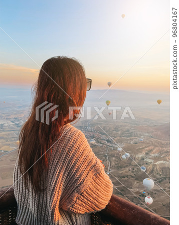 Happy woman during sunrise watching hot air balloons show from a basket in the sky in Cappadocia, Turkey 96804167