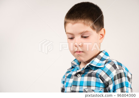 A 4-year-old boy in a plaid blue shirt looks down, squawks or lies, a place for text 96804300