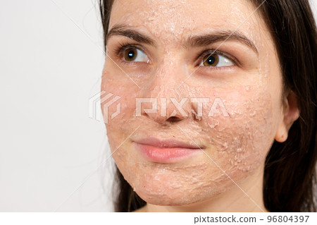 A beautiful young woman applied a scrub or mask to her face, facial skin care, skin cleansing 96804397