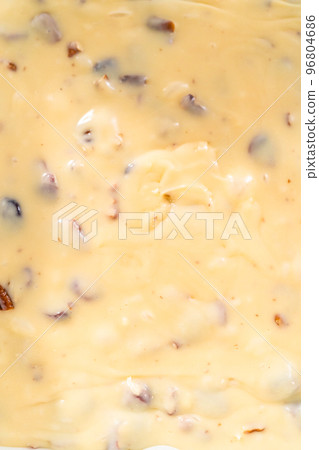 Pouring fudge mixture into the baking pan lined with parchment paper to prepare white chocolate cranberry pecan fudge. 96804686