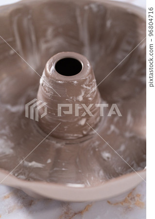 Greasing bunt cake pan to bake apple bundt cake with caramel glaze. Greasing bunt cake pan to bake apple bundt cake with caramel glaze. 96804716