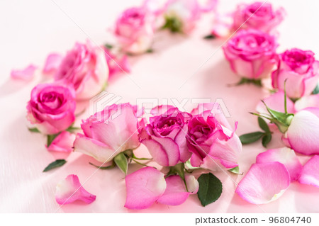 Heart shape made out of pink roses and rose petals on a pink background. 96804740