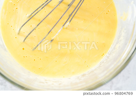 Close up view. Close up view. Mixing ingredients in a glass mixing bowl to bake funfettti bundt cake. 96804769