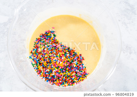 Close up view. Mixing ingredients in a glass mixing bowl to bake funfettti bundt cake. 96804819