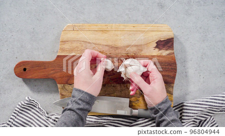 Cutting organic garlic on a wood cutting board. Cutting organic garlic on a wood cutting board. 96804944