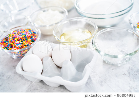 Ingredients in glass mixing bowls to bake funfettti bundt cake. 96804985