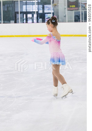 Little girl practicing figure skating on an indoor ice rink. 96805028