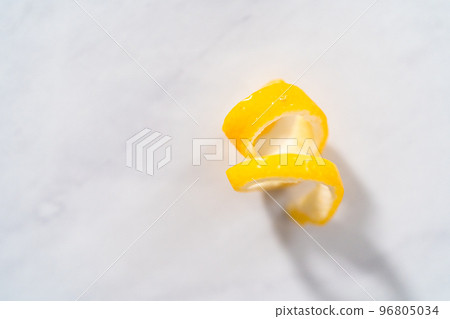 Preparing lemon swirls from the organic lemon to decorate the cocktail. 96805034