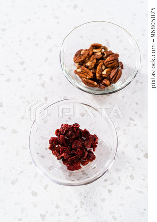 Measured ingredients in glass mixing bowls to make white chocolate cranberry pecan fudge. 96805075