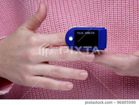 pulse oximeter on the hand of a girl in a pink sweater 96805090