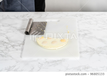 Cutting hard-boiled eggs in a shape of a loaf on a white cutting board. Cutting hard-boiled eggs in a shape of a loaf on a white cutting board. 96805133