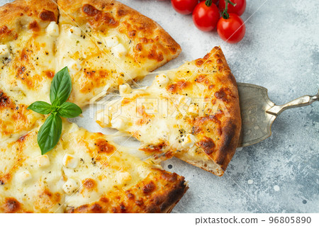 Italian pizza four cheeses with stretching cheese and basil on a light concrete background Italian pizza four cheeses with stretching cheese and basil on a light concrete background 96805890