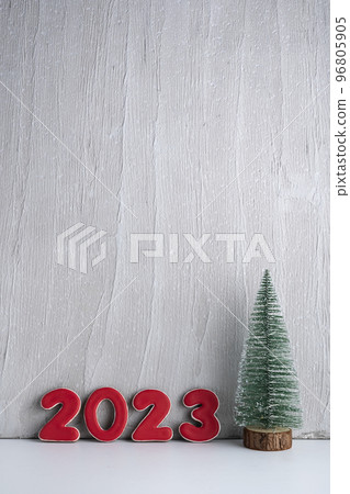 Small artificial Christmas tree and red numbers 2021 against a gray wall. New year concept. Copy space. Vertical frame 96805905