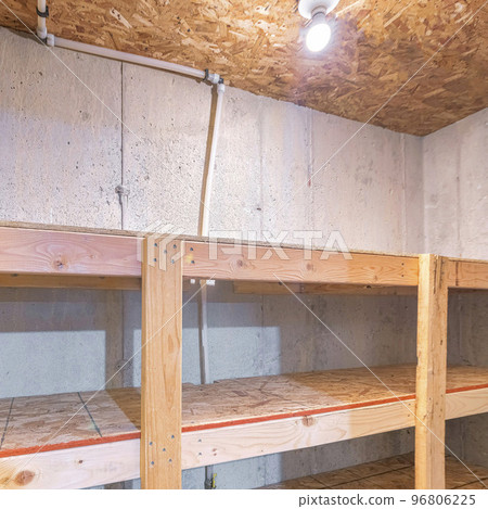 Square Unfinished small storage room with concrete walls and wooden shelves 96806225