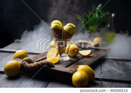 fresh lemon citrus sorbet or ice cream with chopped fresh fruit on the wooden table on the background fresh lemon juice and vase with flowers in a fume. still life ice cream, juice, wood, fume 96806616