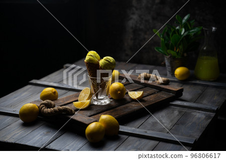 fresh lemon citrus sorbet or ice cream with chopped fresh fruit on the wooden table on the background fresh lemon juice and vase with flowers in a fume. still life ice cream, juice, wood, fume 96806617