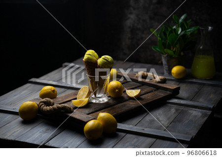 fresh lemon citrus sorbet or ice cream with chopped fresh fruit on the wooden table on the background fresh lemon juice and vase with flowers in a fume. still life ice cream, juice, wood, fume 96806618