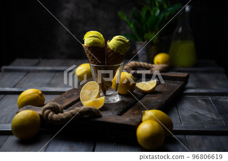 fresh lemon citrus sorbet or ice cream with chopped fresh fruit on the wooden table on the background fresh lemon juice and vase with flowers in a fume. still life ice cream, juice, wood, fume 96806619