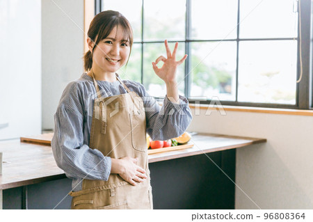 一位亞洲女性,她是家庭主婦、管家和烹飪人員,在家裡的廚房和咖啡館裡穿著圍裙擺出 OK 的姿勢 一位亞洲女性,她是家庭主婦、管家和烹飪人員,在家裡的廚房和咖啡館裡穿著圍裙擺出 OK 的姿勢 96808364