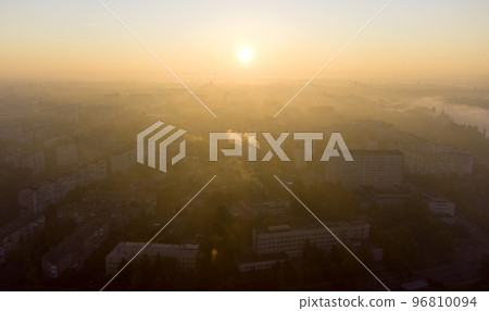 Forest park trees, river and many high-rise buildings in city in early morning at dawn in summer. Brightly shining sun, clear cloudless sky and morning mist Sunbeams and shadows Aerial drone landscape Forest park trees, river and many high-rise buildings in city in early morning at dawn in summer. Brightly shining sun, clear cloudless sky and morning mist Sunbeams and shadows Aerial drone landscape 96810094