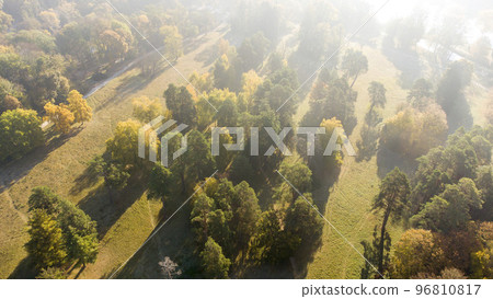 Flying over autumn trees, meadow in park on sunny bright day. Top view. Aerial drone view. Bright sunlight, shining sunbeams rays and sun overexposure. Long shadows. Beautiful natural background 96810817