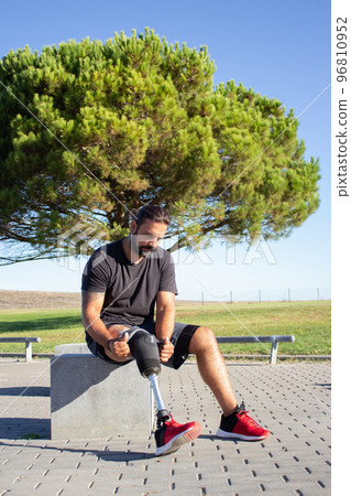 Young sportsman with disability sitting on stone bench 96810952