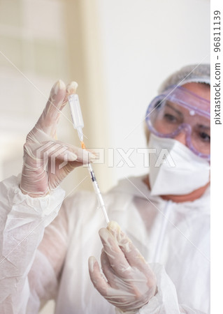 Close-up of female doctor preparing syringe for injection 96811139
