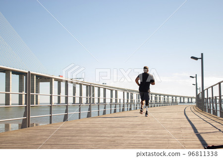 Back view of man with artificial leg jogging on bridge Back view of man with artificial leg jogging on bridge 96811338