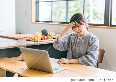 A young housewife Asian woman who is stressed and worried while using a laptop for telework A young housewife Asian woman who is stressed and worried while using a laptop for telework 96812667