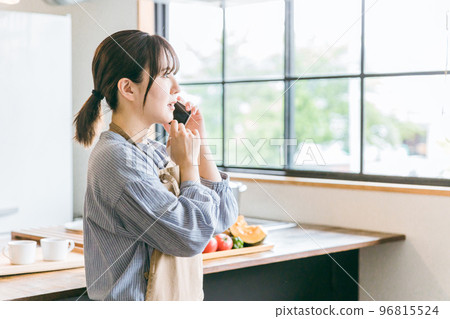 Surprised Asian woman while calling on her smartphone in the kitchen/dining room at home 96815524