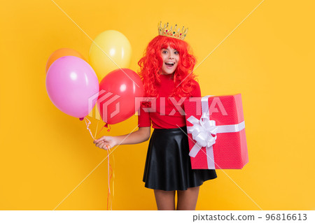 surprised kid in crown with present box and party balloon on yellow background surprised kid in crown with present box and party balloon on yellow background 96816613
